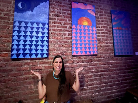 Juanita Ka'ahanui, painter and artist standing with her Triptych of abstract and geometric motifs recording the birth stories of her sons.